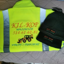 MARTYNA SZWED - Żółta bluza robocza z haftowanym logo 'KIL-KOP' i numerem telefonu, obok czapka z tym samym haftem. Odzież z logo firmy na szarym tle.