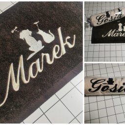 MARTYNA SZWED - Brązowy ręcznik z haftem imienia 'Marek' i sylwetkami psa i kota, obok zwinięty ręcznik z imieniem 'Gosia', zapakowany w folię. Unikatowe wzory i personalizacja.