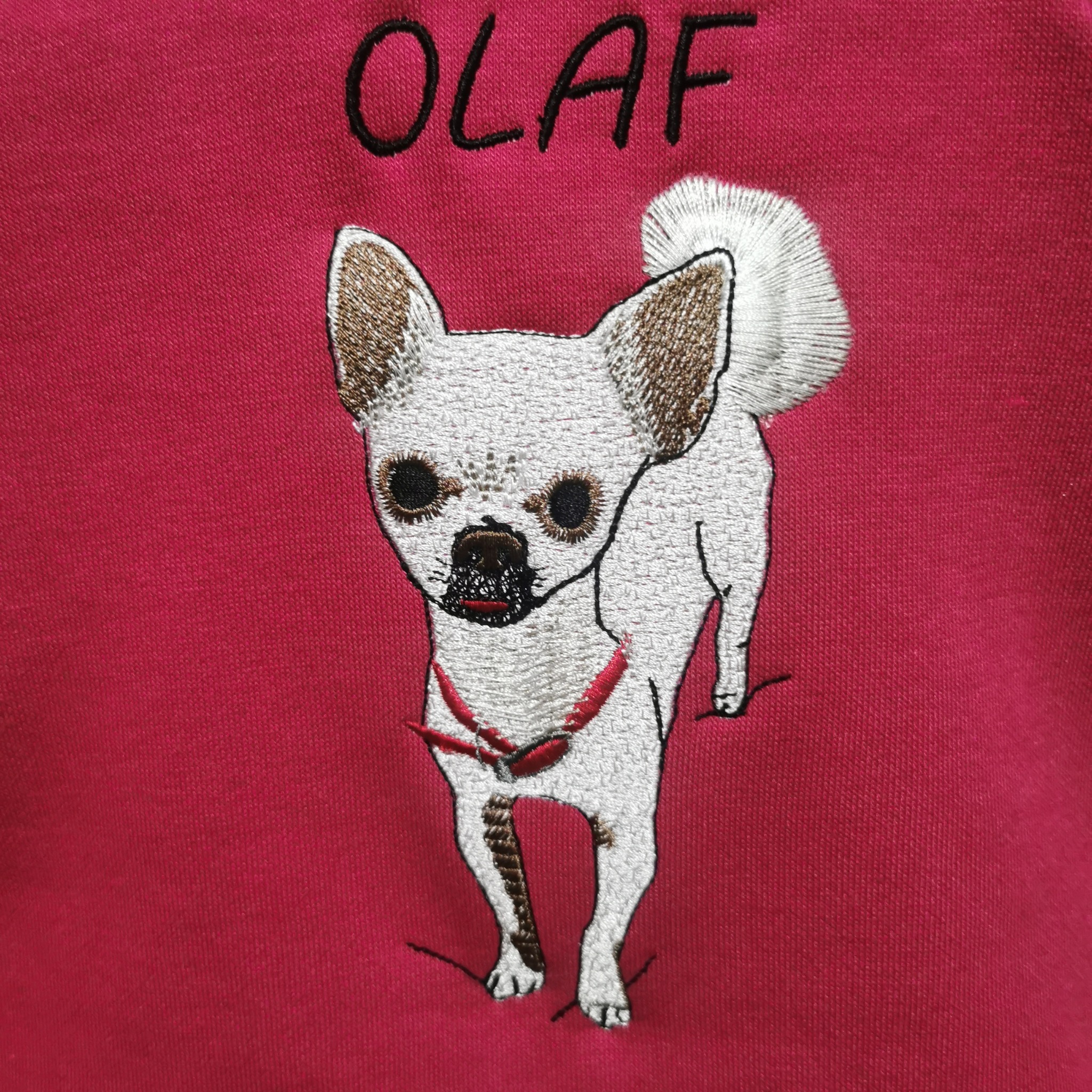 Różowa bluza z haftowanym wizerunkiem psa rasy Chihuahua z imieniem 'OLAF' nad nim. Detal haftu.
