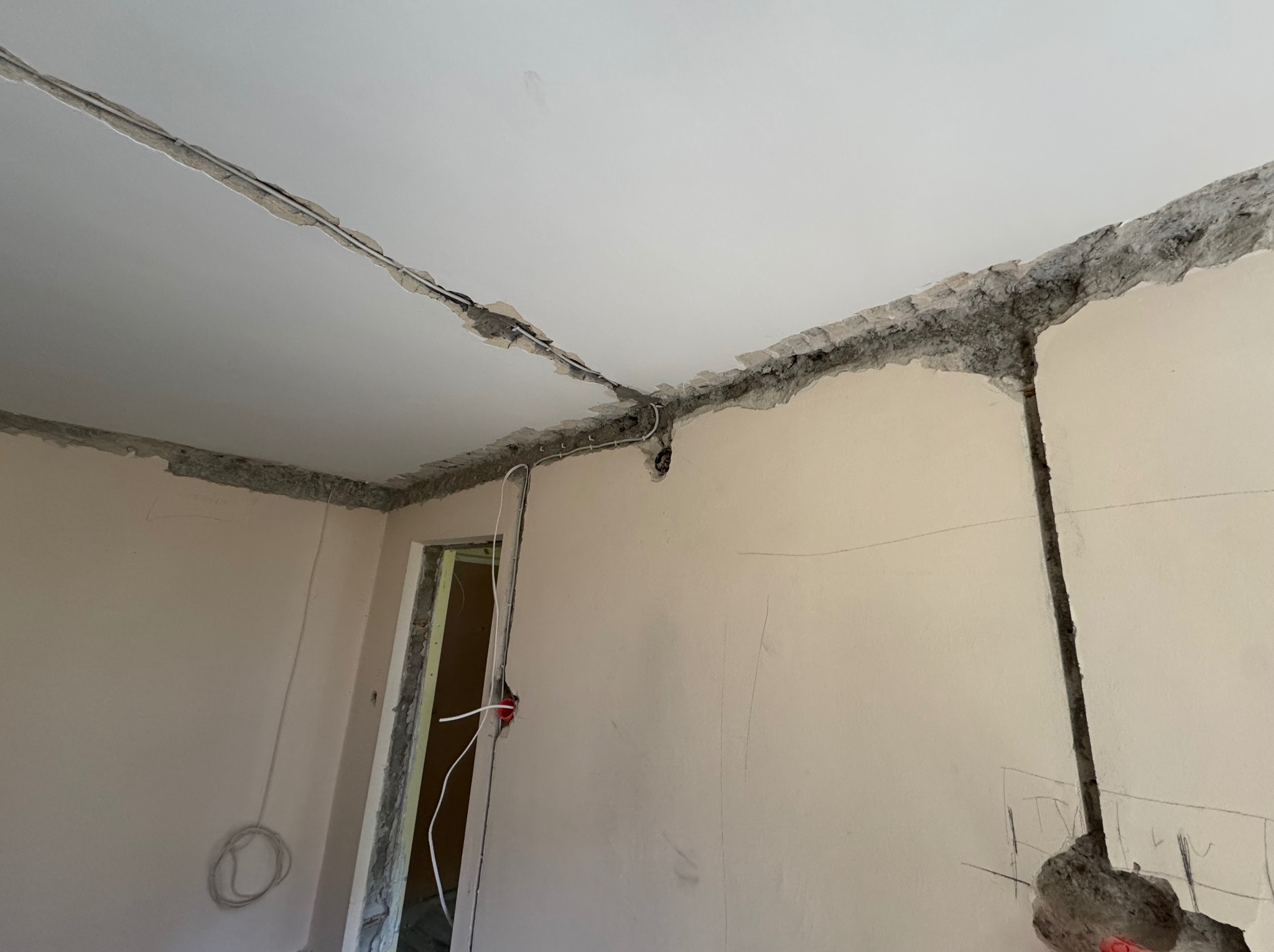 Wykute bruzdy w ścianach i suficie pod instalację elektryczną w surowym wnętrzu. Widoczne przewody i puszki elektryczne. Przygotowanie do montażu instalacji.