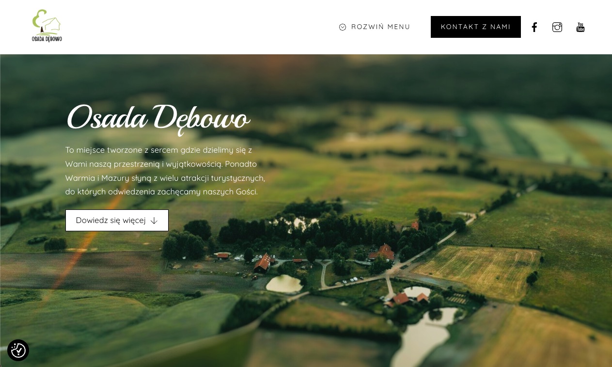Strona www ośrodka eventowego z widokiem na krajobraz Warmii i Mazur. W tle pola i lasy, na pierwszym planie nazwa ośrodka i przycisk 'Dowiedz się więcej'.