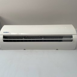 KAP-Instal - Biały klimatyzator Kaisai zamontowany na ścianie, widok z przodu, wnętrze pomieszczenia z białymi ścianami i sufitem.