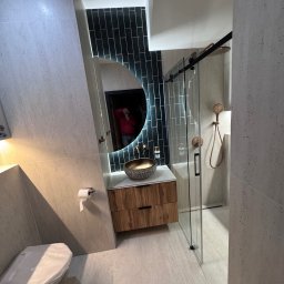 Adr-remonty - Nowoczesna łazienka w Warszawie: umywalka nablatowa z drewnianą szafką, podświetlane lustro, kabina prysznicowa ze złotą armaturą i toaleta z osłoną.