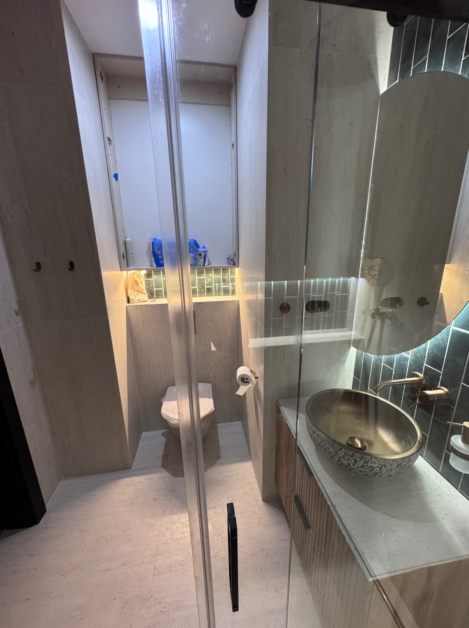 Nowoczesna łazienka z kabiną prysznicową typu walk-in, umywalką nablatową w stylu retro i lustrem z podświetleniem LED. Jasne płytki i minimalistyczny design.