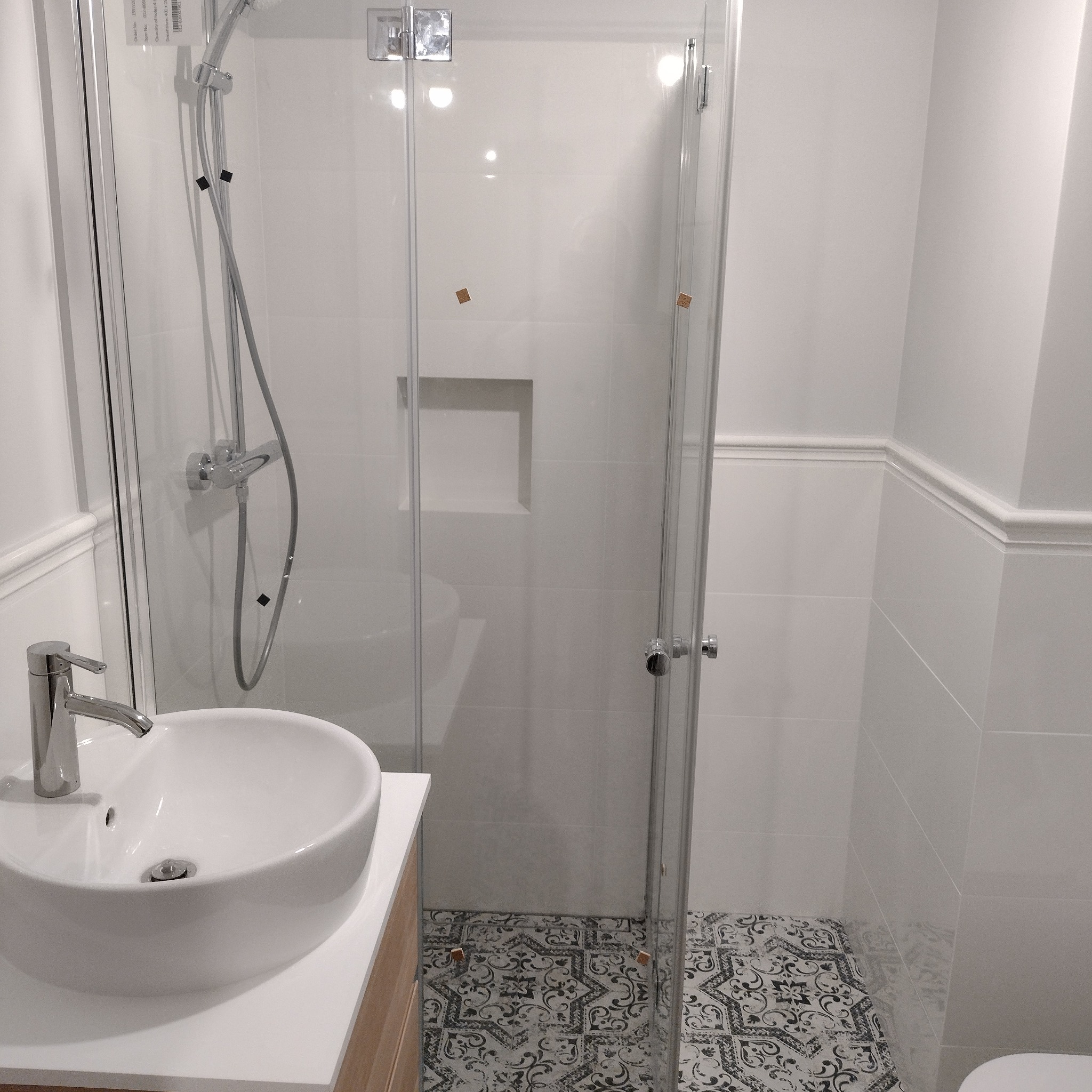 Nowoczesna łazienka z kabiną prysznicową typu walk-in, umywalką nablatową i dekoracyjnymi płytkami podłogowymi w stylu vintage.