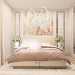 Anna Design by Anna Stenka-Kosińska - Elegancka sypialnia w beżach: łóżko z narzutą, kwiaty w wazonach, abstrakcyjny obraz nad wezgłowiem i nowoczesna lampa. Projekt wnętrza z dbałością o detale.