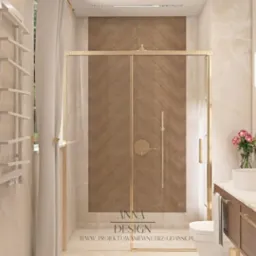 Elegancka łazienka z kabiną prysznicową w złotej ramie, drewnianą ścianą w jodełkę i marmurowymi płytkami. Umywalka nablatowa, subtelne oświetlenie.