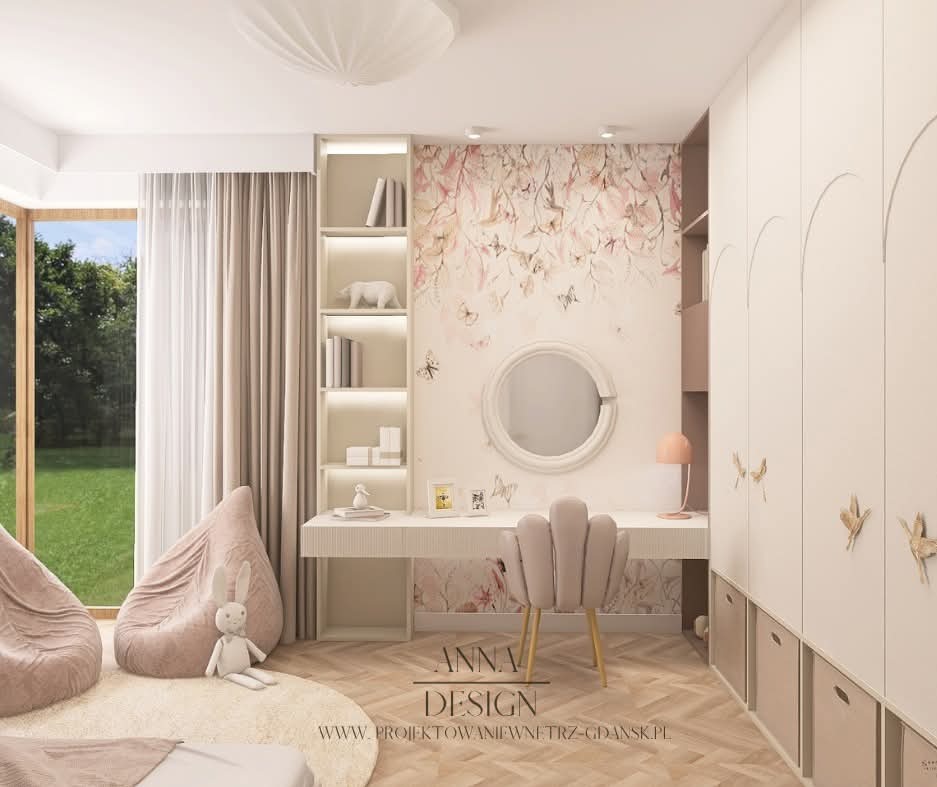 Pokój dziecięcy w pastelowych barwach: tapeta w kwiaty, okrągłe lustro nad biurkiem, pufy i pluszowy królik na dywanie. Szafa w zabudowie z dekoracyjnymi uchwytami.