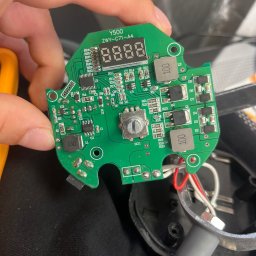 Patryk Kołcon - Zielona płytka drukowana Y500 ZWY-C71-A4 z elementami elektronicznymi, trzymana w dłoni, widoczne układy scalone, rezystory i kondensatory. Kabel zasilający w tle.