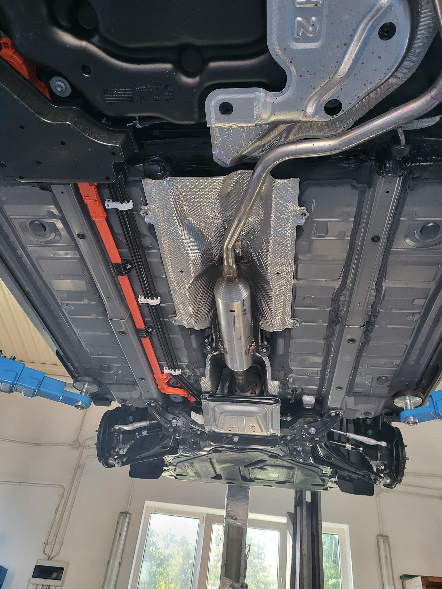 Podwozie samochodu na podnośniku w Łodzi. Widoczne elementy układu wydechowego, przewody i zawieszenie. Przegląd techniczny pojazdu.