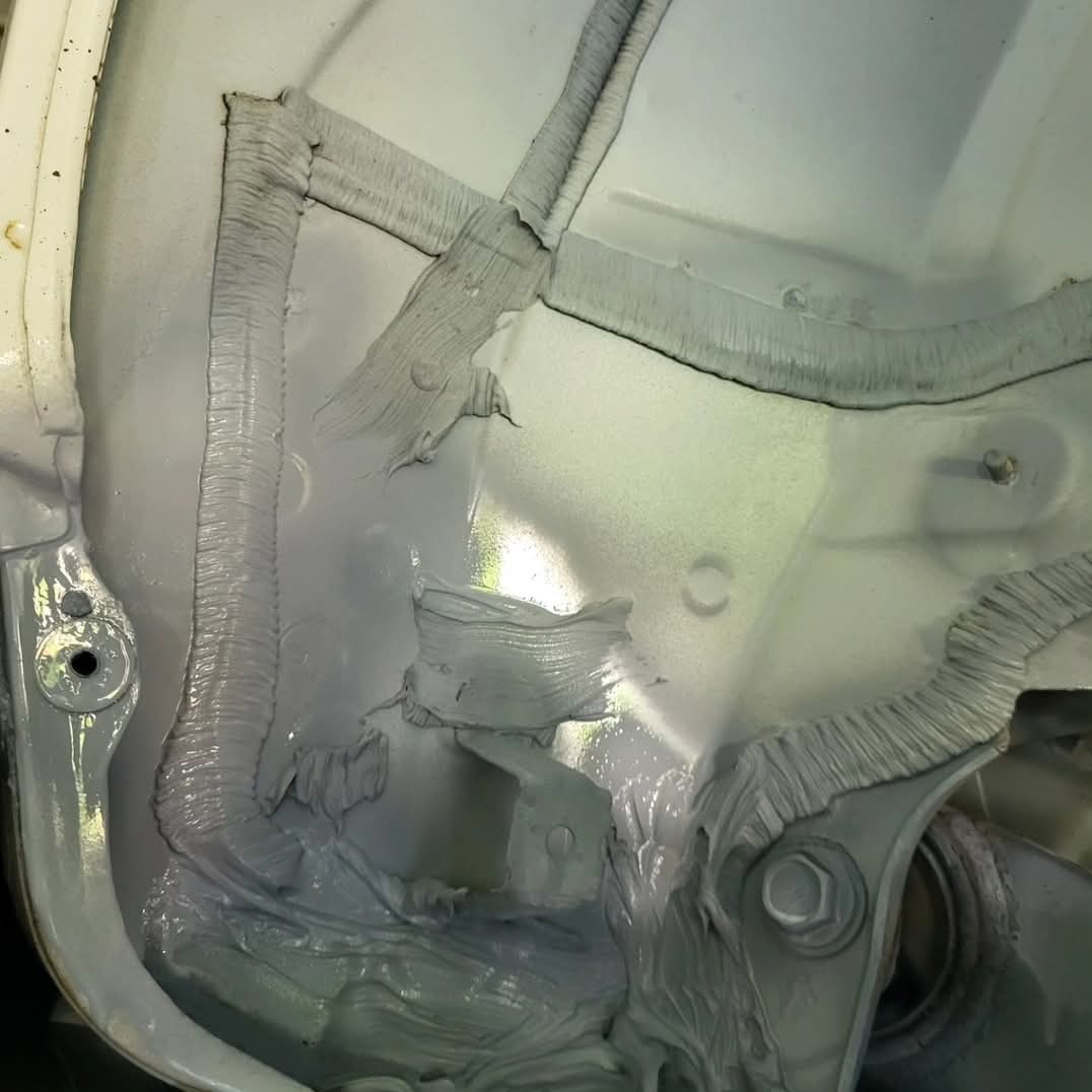 Szczegółowe ujęcie zabezpieczenia antykorozyjnego wewnątrz nadkola pojazdu, z widoczną warstwą ochronną nałożoną na metalowe elementy.