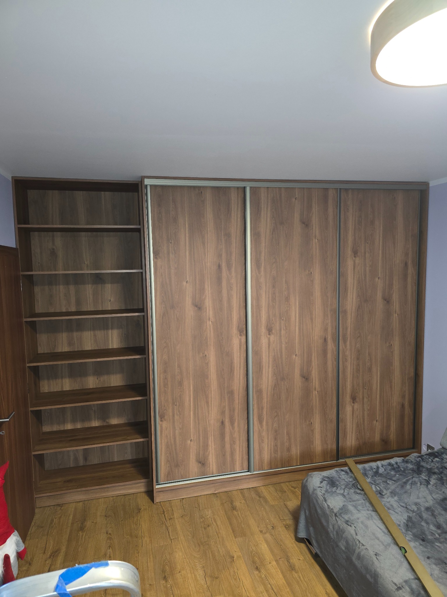 Szafa wnękowa z przesuwnymi drzwiami i regałem w odcieniach brązu, wykonana na wymiar w Kleczy Górnej. Widoczna struktura drewna i metalowe prowadnice.