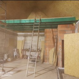 EFEKT - Wnętrze w trakcie prac wykończeniowych: rusztowanie, drabina oparta o ścianę z cegieł, widoczne płyty OSB na ścianach i suficie. Etap budowy antresoli.