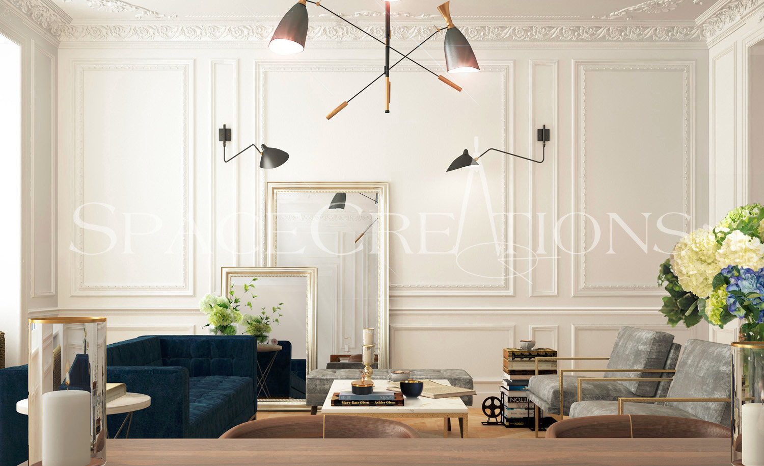 Elegancki salon w stylu klasycznym z granatową sofą, szarymi fotelami, lustrami w złotych ramach i dekoracyjnym oświetleniem. Widok zza drewnianego blatu.