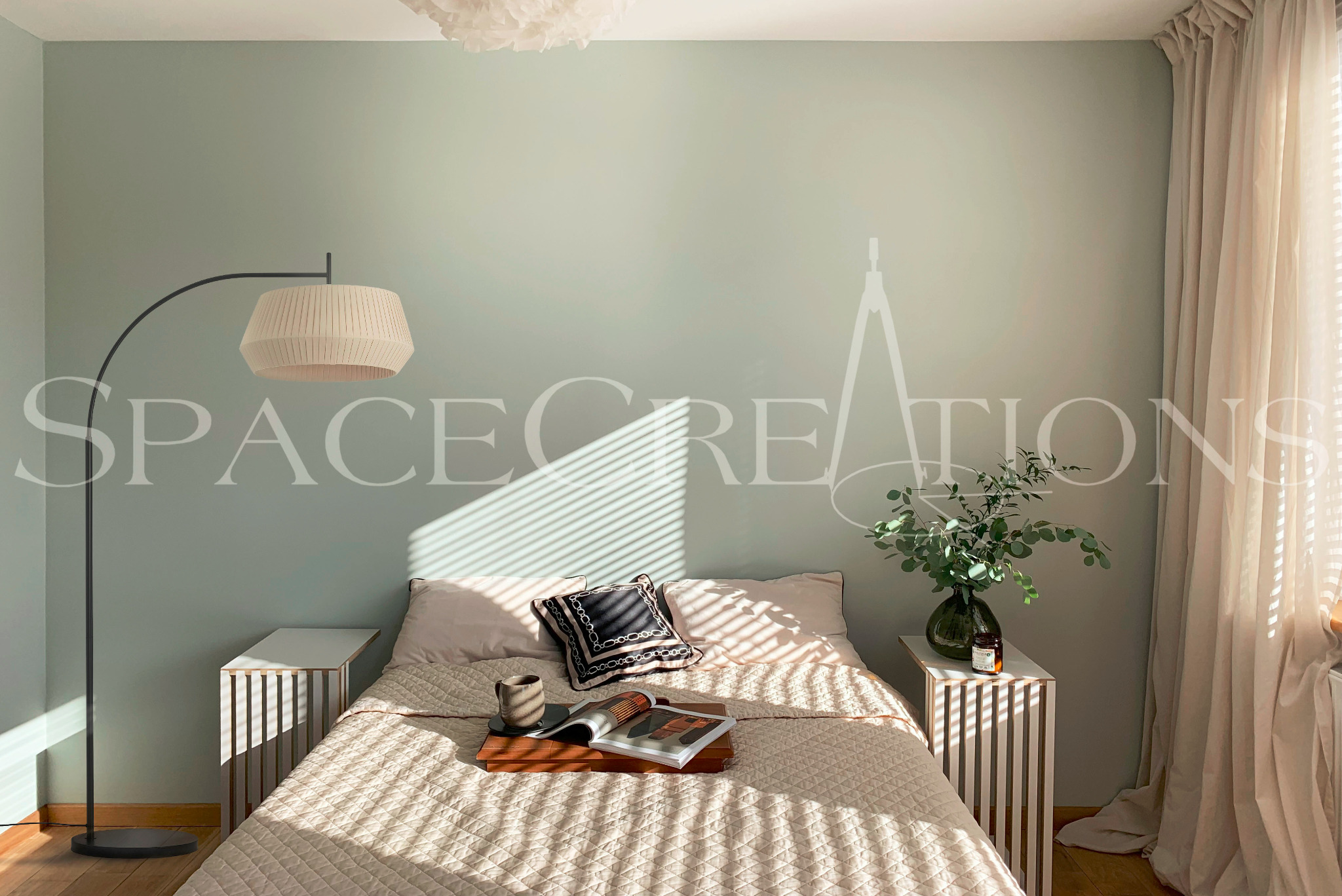 Jasna sypialnia z łóżkiem, stolikami nocnymi i lampą łukową. Na ścianie delikatny wzór. Promienie słońca wpadają przez okno z beżowymi zasłonami.