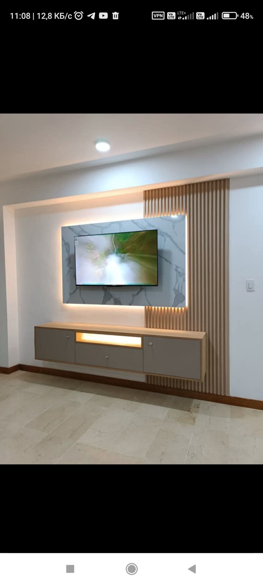 Wykończenie ściany TV z marmurowym panelem i drewnianymi lamelami. Podwieszana szafka RTV z oświetleniem LED. Nowoczesny design wnętrza salonu.