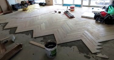 Układanie płytek na posadzce w układzie jodełka.