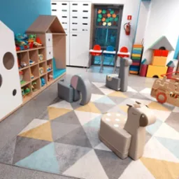Kolorowa sala zabaw z drewnianymi zabawkami w kształcie zwierząt, regałami z zabawkami i stolikami do karmienia. Dywan w geometryczne wzory.