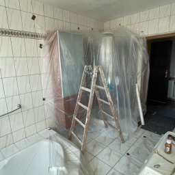 PatPro Bau - Łazienka w trakcie remontu: zabezpieczone folią meble, wanna i podłoga. Stara, drewniana drabina oparta o ścianę. Przygotowanie do malowania sufitu.