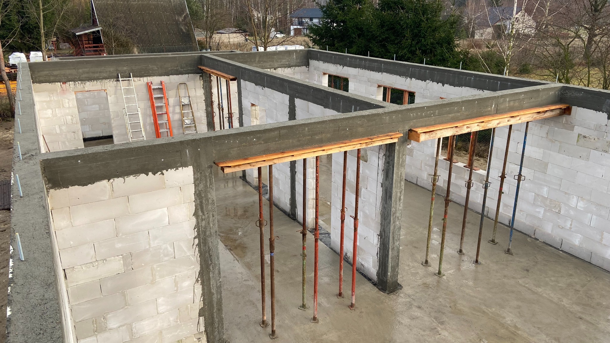 Budowa domu z betonu komórkowego: ściany, wieniec żelbetowy, stemple budowlane, drabiny. Widok z góry na surowy stan.