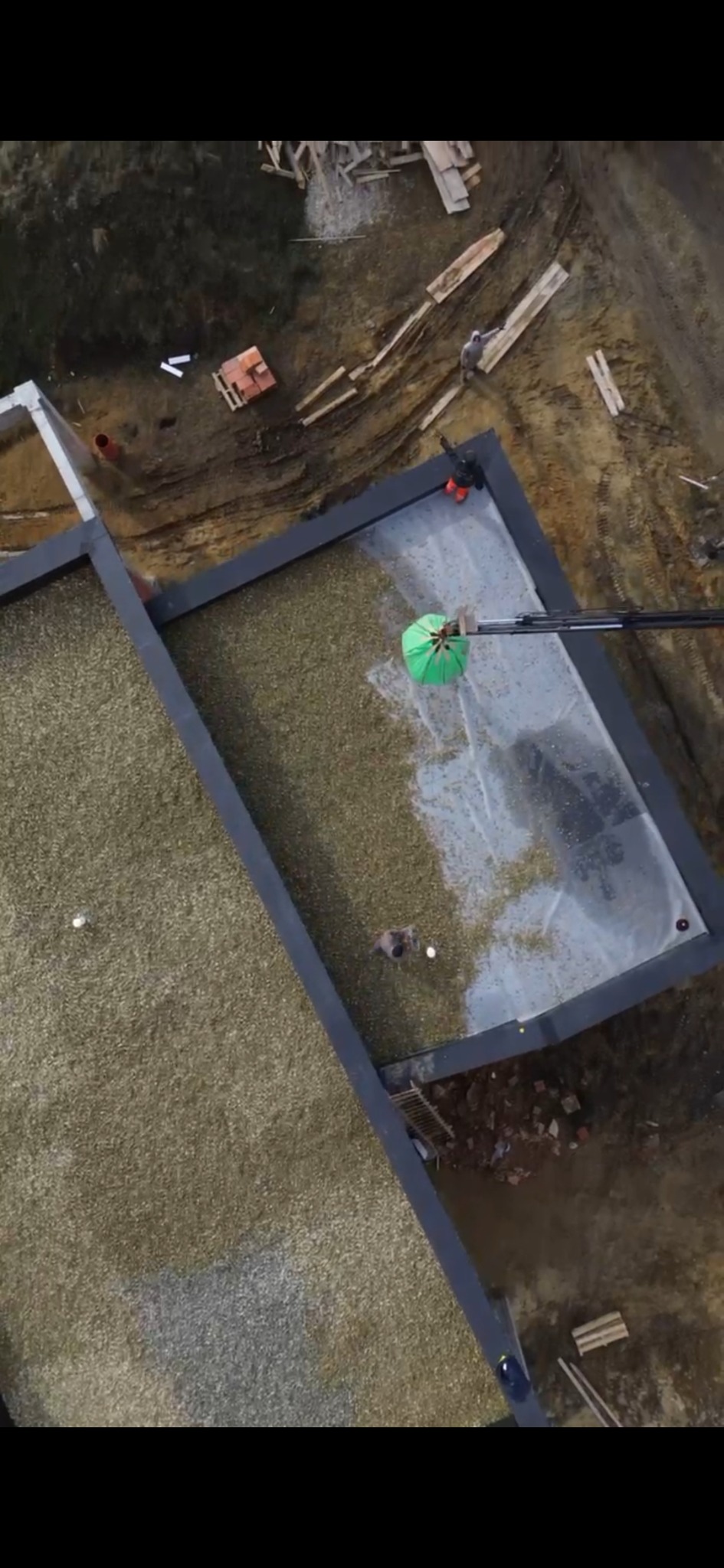 Widok z góry na dach z zielonymi elementami, prawdopodobnie podczas prac związanych z jego budową lub renowacją. Na dachu widoczni pracownicy i sprzęt budowlany.