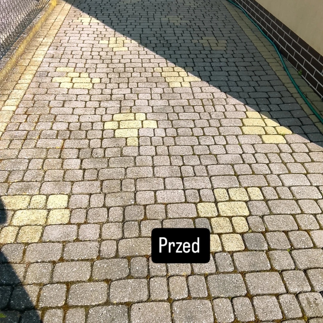 Kostka brukowa przed czyszczeniem, widoczne zabrudzenia i mech między kostkami. Częściowo zacieniona powierzchnia. Ujęcie z góry, perspektywa zbieżna.