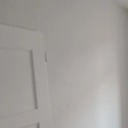 Białe, odświeżone wnętrze po remoncie: gładkie ściany pomalowane na biało, widoczna biała stolarka drzwiowa i okienna. Minimalistyczny design po renowacji.