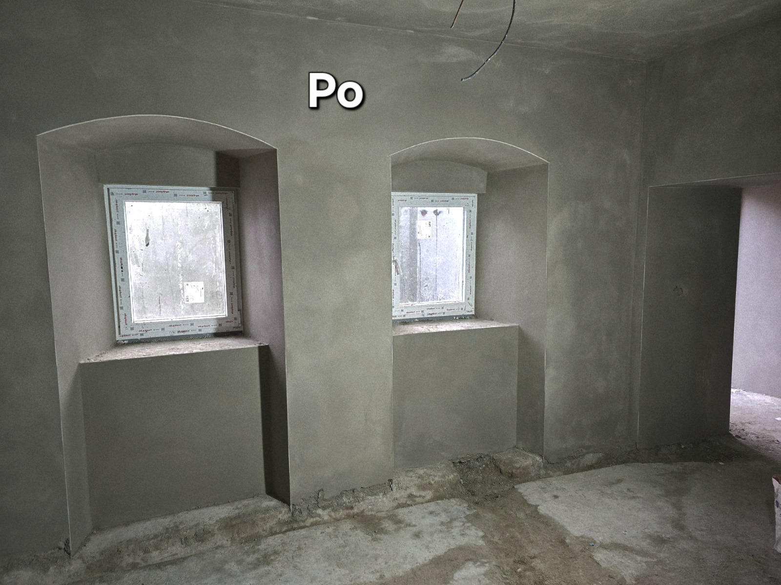 Wnętrze po tynkowaniu maszynowym: gładkie, szare ściany z oknami w niszach. Widoczny fragment podłogi. Napis 'Po' sugeruje etap po wykonaniu usługi.
