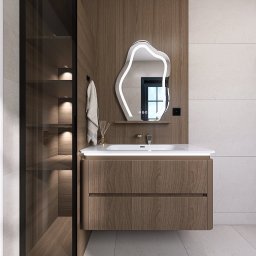 Studio Projektu - Olga Czekalska - Nowoczesna łazienka z szafką pod umywalką z forniru, podświetlanym lustrem o nieregularnym kształcie i wysoką szafką z przeszklonym frontem, oświetloną od wewnątrz.