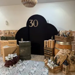 Scenografia urodzinowa w stylu gangsterskim: rekwizyty z beczką, skrzyniami, workami z symbolem dolara i atrapami pieniędzy, czarne tło z liczbą 30.