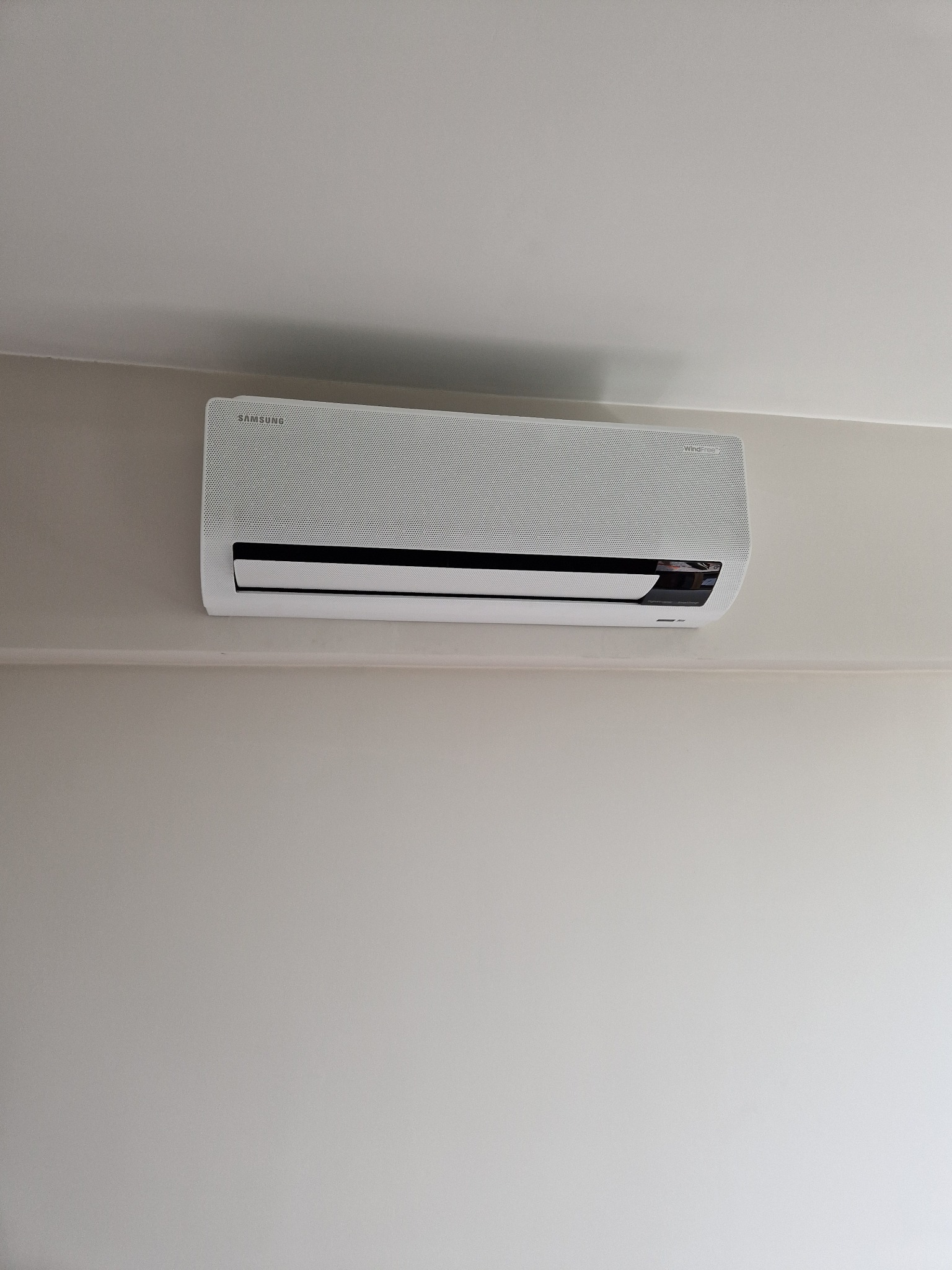 Zamontowany klimatyzator Samsung WindFree na ścianie w Łodzi. Widoczny z bliska, na jasnym tle ściany. Minimalistyczny design urządzenia.