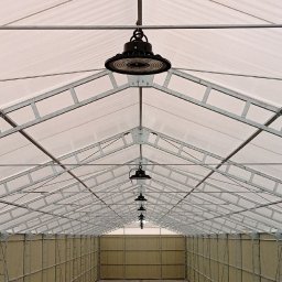 ALIAKSANDRA KASTSIUKEVICH - Wnętrze hali z metalową konstrukcją dachu i rzędem okrągłych lamp LED, oświetlających przestrzeń. Widok perspektywiczny w głąb hali.