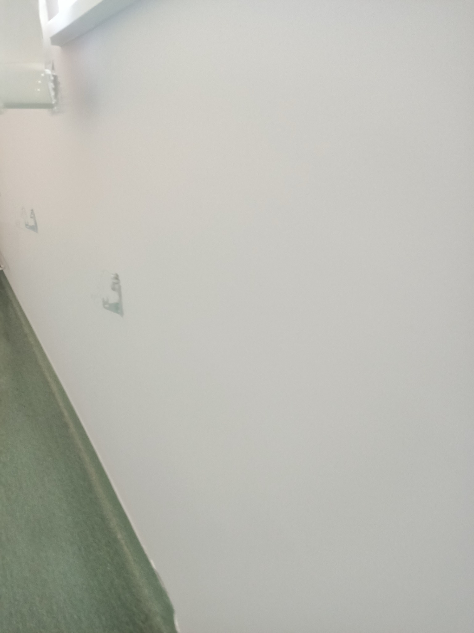 Ściana po szpachlowaniu w Kobylance, przygotowana do malowania. Widoczne ślady po mocowaniach i gładka powierzchnia.