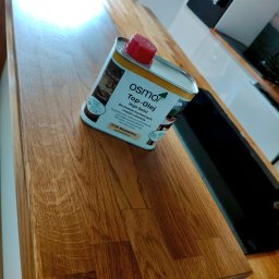 Renesans drewna - Olej do blatów Osmo na drewnianym blacie kuchennym. Produkt do impregnacji drewna, bezbarwny, jedwabisty. Widoczny fragment blatu po olejowaniu.