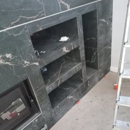 Marek Szpakowski - Czarny marmur z białymi żyłkami tworzący wnęki ścienne, częściowo widoczna drabina. Wykończenie wnętrza w trakcie prac, z widocznymi akcesoriami i elementami montażowymi.