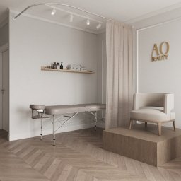Aleksandra Ciesielska Architektura - Jasne, minimalistyczne wnętrze salonu kosmetycznego z leżanką, krzesłem na podeście i logo 'AO Beauty' na ścianie. Parkiet w jodełkę i delikatne oświetlenie.