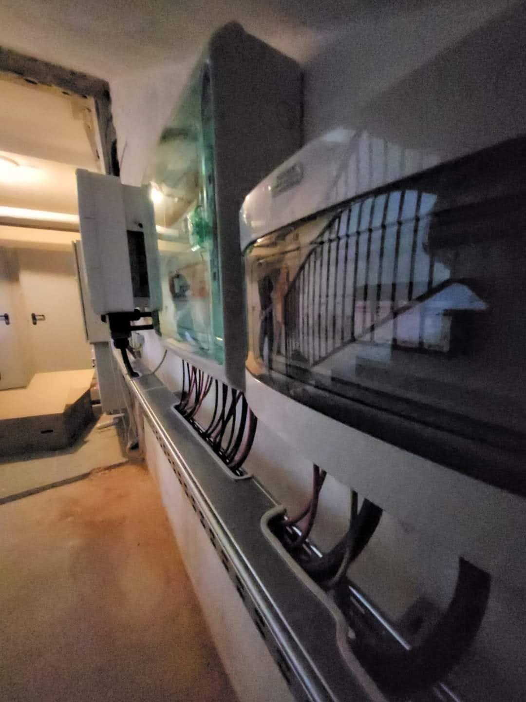 Szyna z przewodami w ścianie, prawdopodobnie instalacja elektryczna w trakcie montażu. Widoczne kable i elementy montażowe, surowe wykończenie wnętrza.