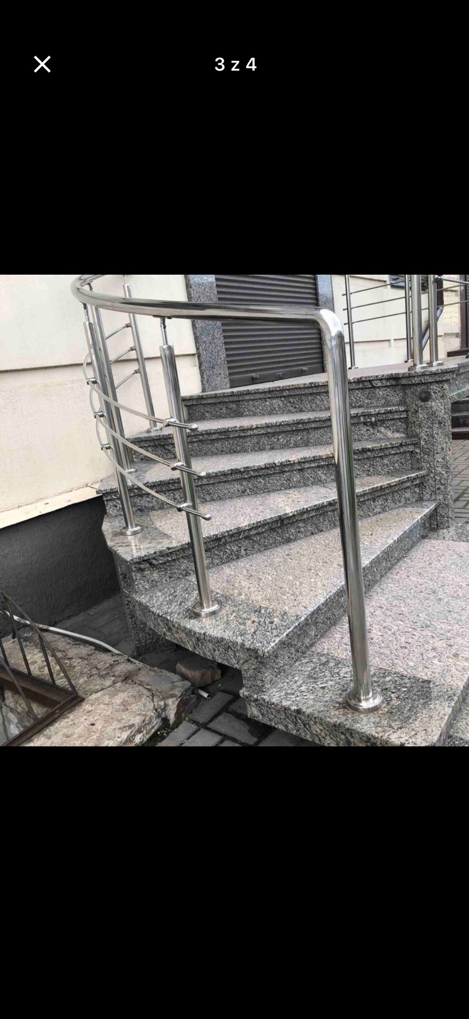 Zewnętrzne schody z szarego granitu z metalową balustradą, prowadzące do budynku. Widoczne detale wykończenia i faktura kamienia.