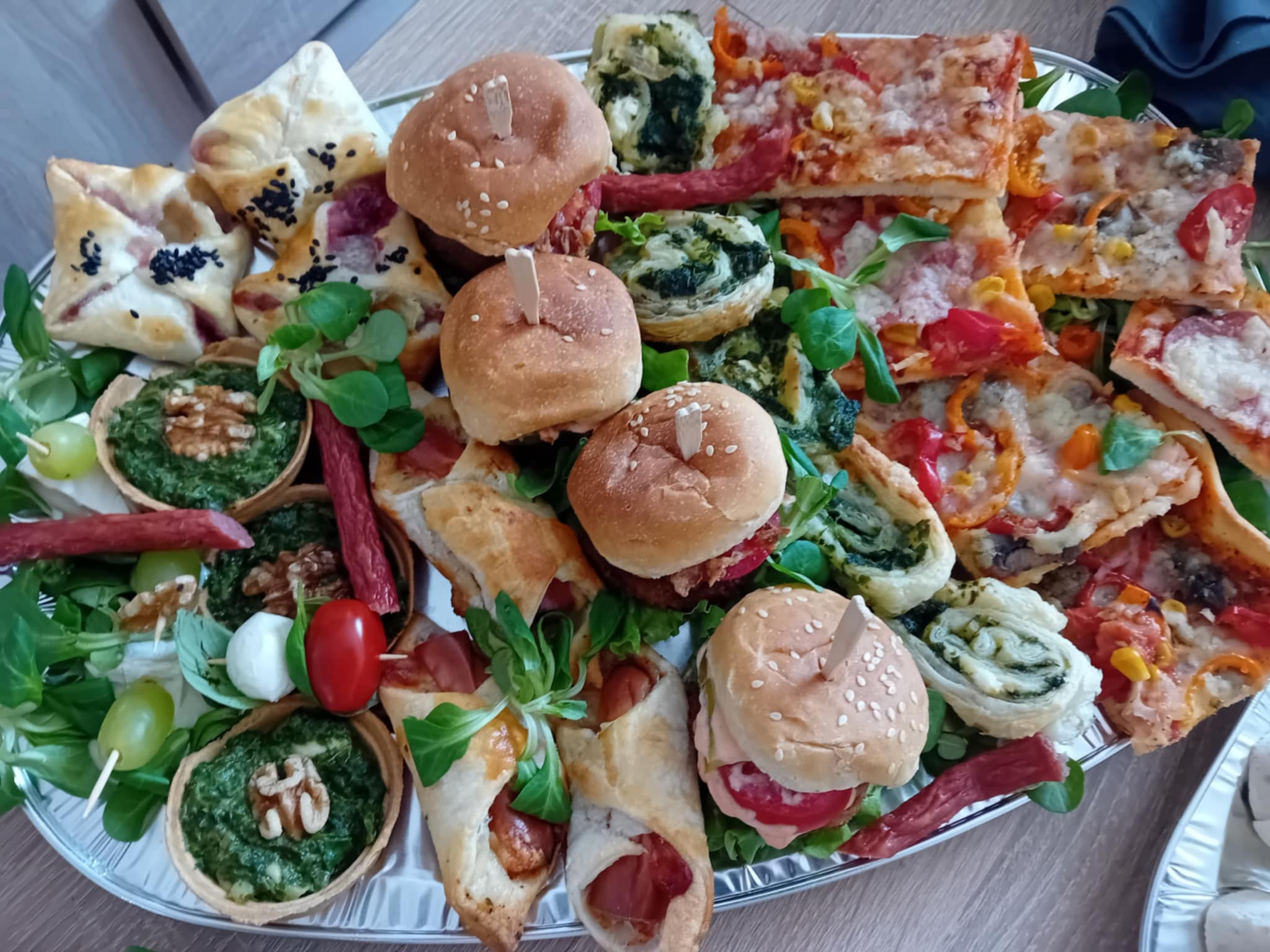 Dekoracyjna taca z mini burgerami, tartaletkami ze szpinakiem, pizzą i przekąskami z ciasta francuskiego, idealna na catering imprezowy.