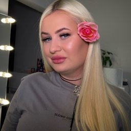 Makeup.Brows - Portret kobiety z blond włosami i różą we włosach, wizaż z błyszczącym wykończeniem, subtelna biżuteria, oświetlenie studyjne z lustrem.