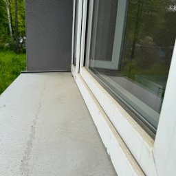 Przytulny dom - Brudny parapet i rama okienna z widocznymi zaciekami i zabrudzeniami. Widok z boku, zieleń w tle.