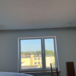 Usługi budowlane illia Zakhariv - Wnętrze pokoju z oknem i zamontowaną listwą oświetleniową pod sufitem. Widoczne przygotowania do montażu oświetlenia. Świeżo pomalowane ściany.