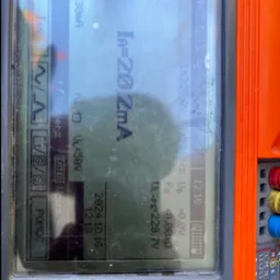 Miernik elektryczny w trakcie pomiaru prądu upływu, wskazujący wartość 20,2 mA. Widoczny ekran z datą 2024.10.16 i napięciem UL-PE 229,7V.