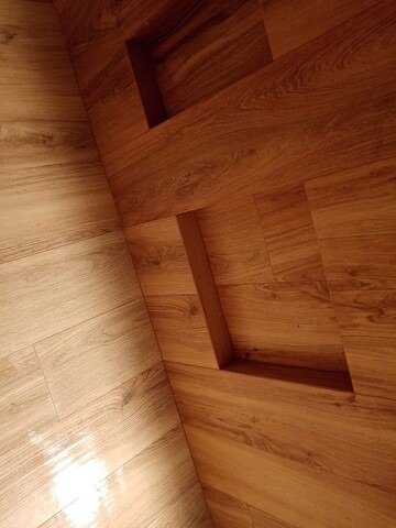 Ukończona podłoga z paneli w dwóch odcieniach brązu, z wbudowanymi półkami w ścianie, ułożona pod kątem, widok z góry.