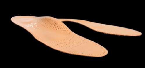 Beżowe skórzane wkładki do butów z precyzyjnymi perforacjami na czarnym tle. Detal cięcia laserowego widoczny na powierzchni wkładki.