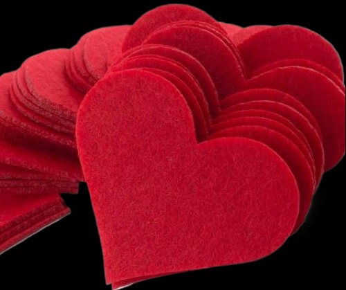 Czerwone, filcowe serca, wycięte laserowo, ułożone warstwami na czarnym tle. Widoczna faktura filcu i precyzyjne krawędzie cięcia.