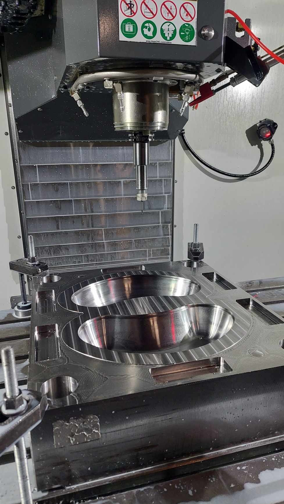 Obróbka metalu na frezarce CNC: precyzyjne wycinanie formy w metalowym bloku. Widoczne narzędzie skrawające i chłodziwo. Detal w trakcie procesu obróbki.