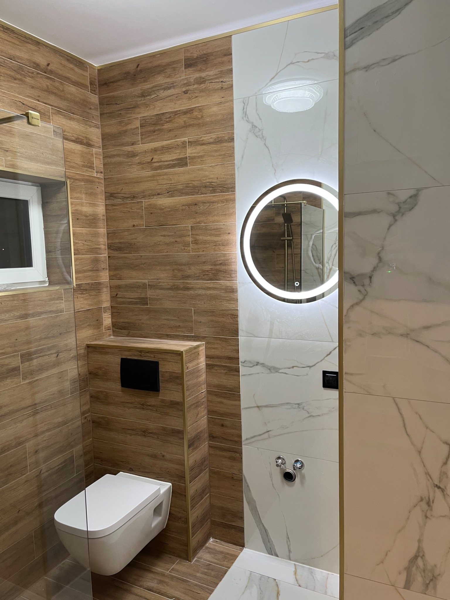 Nowoczesna aranżacja łazienki we Wrześni: drewnopodobne i marmurowe płytki, podświetlane lustro, wisząca toaleta. Eleganckie wykończenie.