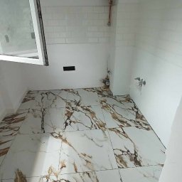 MAYSTER - Wykończona łazienka z marmurową podłogą i białą glazurą w Jeleniej Górze. Widoczny bojler i okno. Charakterystyczny wzór płytek podłogowych.