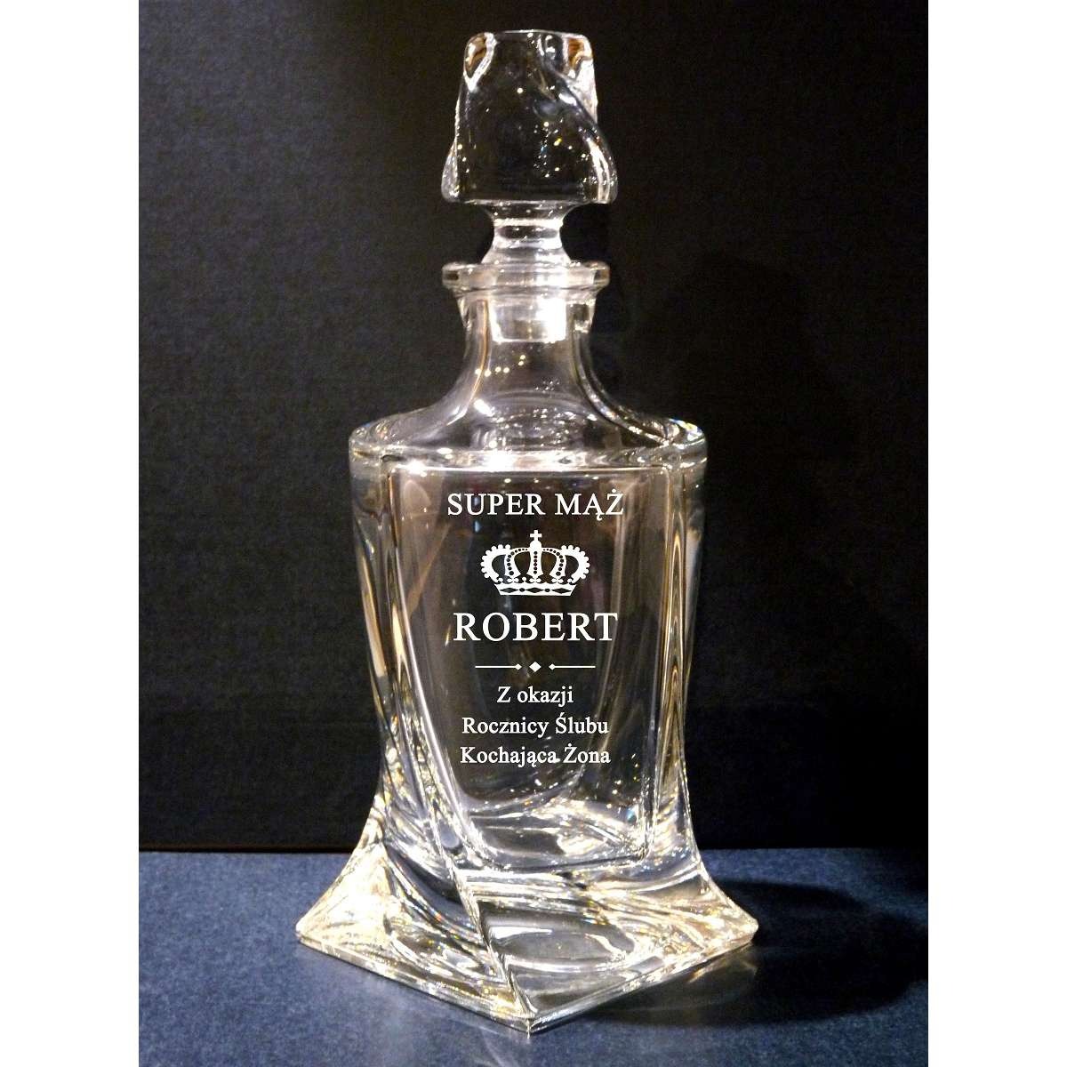 Karafka z grawerem 'Super Mąż Robert' i koroną, prezent na rocznicę ślubu od kochającej żony. Szklany, elegancki upominek na ciemnym tle.